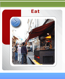 Street food vendor preparing crepes at a stall in Rue Mouffetard, Paris, with customers waiting on the cobblestone street